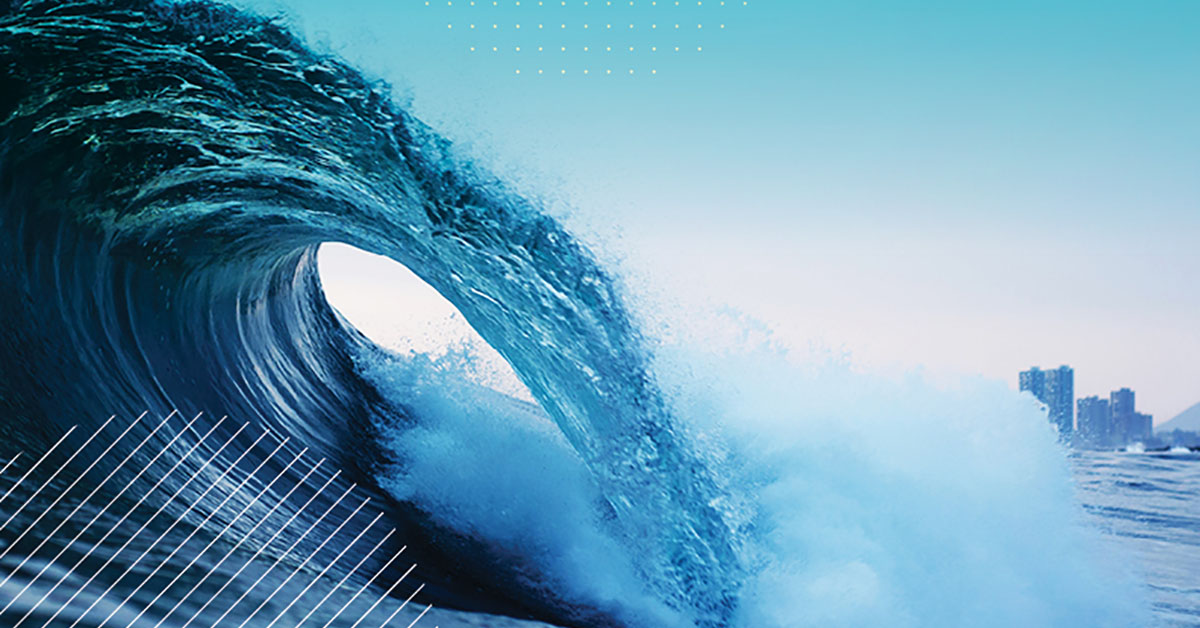A barrel wave in the ocean with a city in the background