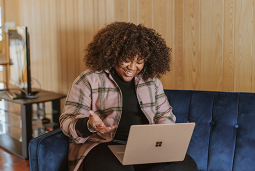A young black woman smiling at a laptop