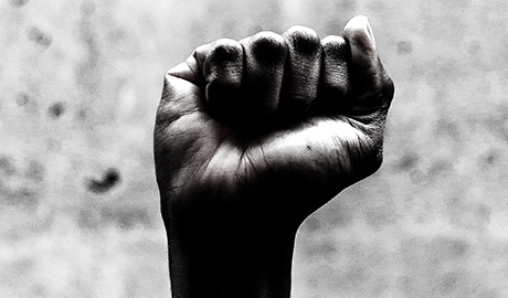 a black and white photo of a black person's hand raised in a fist