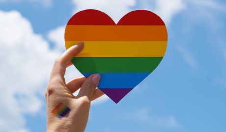 A hand holding a rainbow heart