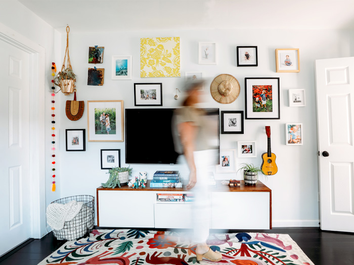 Living room with frames on wall and someone blurred out walking in front of camera
