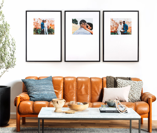 Couch leaning against wall with framed photos of families above