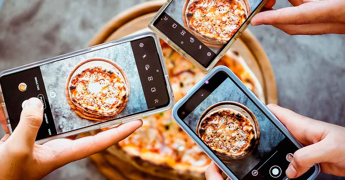 Hands taking photos of their pizza