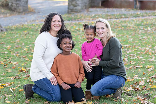 Amie Crawford, wife, and their two daughters smiling at camera.