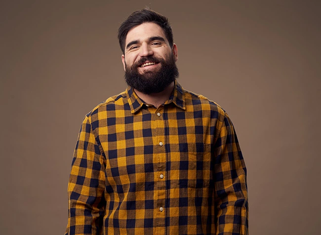 Bearded man in flannel smiling at camera