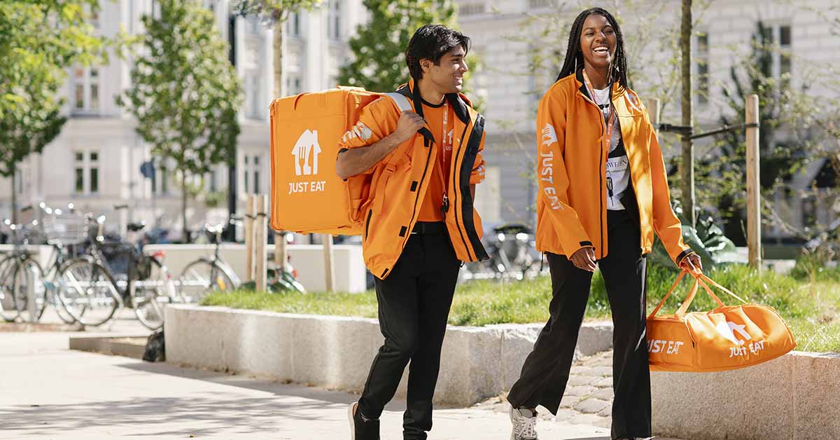 Two food delivery people walking on street