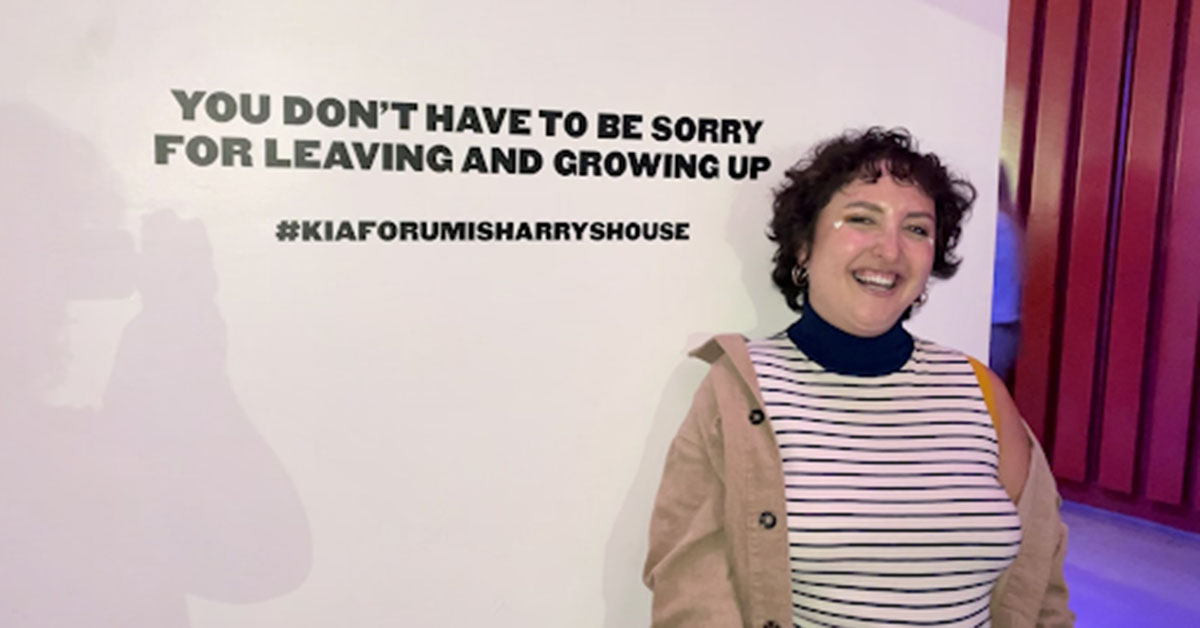 Madeline standing in front of sign that reads: