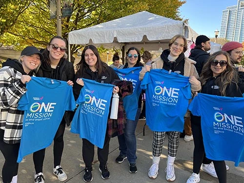 3Q/DEPTsters holding up t-shirts that say "One Mission to end breast cancer"