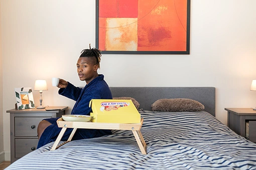 Man sitting on bed with breakfast tray
