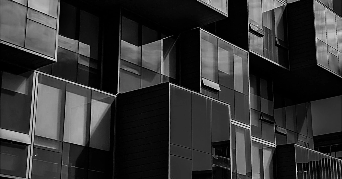 A black and white photo of the face of a primarily glass building